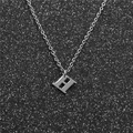 Close-up of a silver stainless steel necklace featuring a bold letter H pendant on black - Steel H
