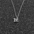 Detailed close-up of a silver stainless steel initial letter M pendant on a dark background - Steel M