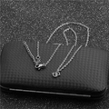 Close-up of silver chain necklace featuring a bold letter S pendant on a dark texture - Steel S