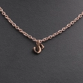 Close-up of rose gold letter necklace on black leather background with fine chain details - Rose Gold S