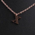 Macro view of rose gold stainless steel letter X pendant necklace on black texture - Rose Gold X