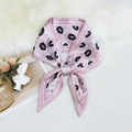 Pink narrow silk scarf featuring black lip prints tied in a bow on a plush background - Lips Pink