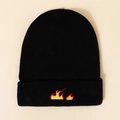 Flat lay of black knit beanie featuring vibrant red and yellow flame embroidery detail - M (56-58cm) / Black
