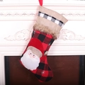 Calza natalizia a quadri rossi e neri con Babbo Natale appesa su un camino bianco - Babbo Natale