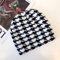 Detailed close-up of a black and white houndstooth knit beanie hat on a fashion magazine - Houndstooth