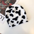 Close-up of black and white cow print knit beanie hat with thick warm texture - Cow Print
