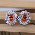 Macro view of sun-shaped earrings featuring orange zircon center and silver claw setting - Stud Earrings / Champagne