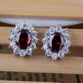 Classic silver stud earrings featuring oval red sapphire and halo cubic zirconia stones - Stud Earrings / Garnet Red