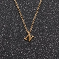 Close-up of golden geometric necklace featuring a polished letter N pendant on black background - Gold N
