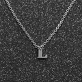 Macro shot of silver stainless steel necklace with capital letter L pendant on glittery background - Steel L