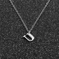 Close-up of a silver stainless steel letter U pendant necklace on a black glitter background - Steel U