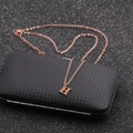 Close-up of rose gold H letter pendant on a textured black box with fine grid pattern - Rose Gold H