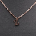 Macro detail of rose gold letter Z pendant on a textured black leather background - Rose Gold Z