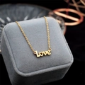 Collana dorata con pendente LOVE e cuore su una scatola per gioielli in velluto grigio - Stile Love