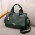 Dunkelgrüne Leder-Boston-Tasche mit Doppelgriffen und Schultergurt auf Sofa - Grün