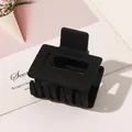 Detail of matte black geometric hair claw clip with rectangular cutout on a white prop - Small Rectangular - Matte Black
