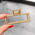 Details einer geometrischen rechteckigen Haarklammer aus Metall in glänzendem Gold - Mittleres Goldrechteck