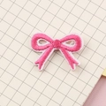 Pink and white bow-shaped embroidery patch with 3D texture on minimalist grid background - Peach Pink