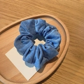 Close-up of a blue corduroy scrunchie placed on a wooden tray with a decorative card - Blue