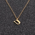 Macro shot of a polished golden stainless steel letter U pendant necklace on black background - Gold U