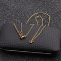 Detailed view of a gold horseshoe necklace chain displayed on a textured black jewelry box - Gold S