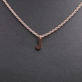 Close-up of rose gold letter J pendant on a fine chain over black leather background - Rose Gold J