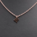 Macro shot of rose gold letter R pendant on O-chain against black leather surface - Rose Gold R
