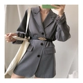 Close-up of a women's skinny black belt with a gold leaf buckle on a grey blazer - Black