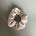 Gros plan d'un chouchou en cuir PU beige avec une texture douce et un design élégant - Version normale / Poche zippée