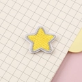 Yellow star embroidered patch with white stitched edges on decorative stationery background - Yellow