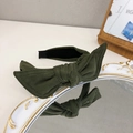 Elegant green velvet headband with a large bow detail displayed on a vintage mirror - Dark Green