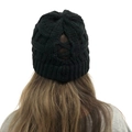 Macro view of black cable knit ponytail beanie featuring elastic criss-cross back opening - Black