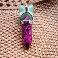 Dual-pointed hexagon stone pendant featuring green and magenta stones on woven texture - Purple Spotted Jasper