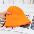 Detailansicht der dicken orangefarbenen Strickmütze auf weißem Holzuntergrund - Hohe Elastizität / Hellorange