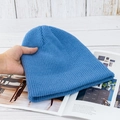 Detailansicht der Rippstrickstruktur einer blauen Wintermütze auf einem Holzhintergrund - Hohe Elastizität / Hellblau