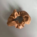 Dettagli della texture di un elastico per capelli in finta pelle cammello con pieghe - Versione normale / Marrone