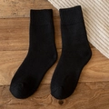 Warm black thick wool knit socks for women laid flat on a rustic wooden floor - One Size / Black