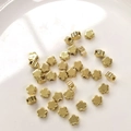 Vista macro di perle distanziatrici a fiore riempite in oro 14K su vassoio per gioielleria - Fiore di Prugno 5mm / Placcato Oro 14K