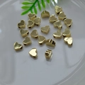 Detail of 14K gold-filled heart-shaped beads scattered on a white plate for DIY jewelry - Heart 7x6mm / 14K Gold Plated