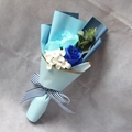 Detail of blue soap flower bouquet with roses and striped ribbon on grey fabric - Blue