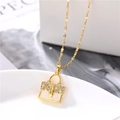 Goldene Halskette mit Handtaschen-Anhänger und Kristallsteinen auf weißem Teller - Taschenanhänger (Lippenkette) / Gold