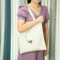 Detail view of beige canvas tote bag with Japanese text print shown worn by a model - Charge Please