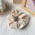 Elegant champagne gold velvet scrunchie hair tie with soft plush texture on white woven surface - Champagne