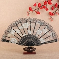 Elegant black lace folding fan with gold floral embroidery on a wooden stand - Fan / Black