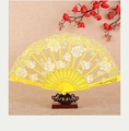 Detailed view of a yellow lace folding fan with floral patterns on a wooden display stand - Fan / Yellow