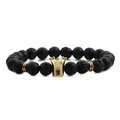 Macro shot of black volcanic lava stones and golden crown charm on a men's bracelet - Lava Stone Gold Crown