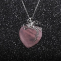 Collar con colgante de corazón rosa y lazo plateado sobre un fondo centelleante - Colgante de Cuarzo Rosa Corazón con Lazo / Rosa