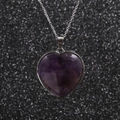 Collana minimalista in acciaio inossidabile con ciondolo a cuore viola su sfondo - Ametista
