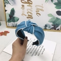 Blue denim knotted headband with white piping detail held against a stylish background - Medium Blue