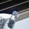 Macro close-up of a sparkling round-cut moissanite ring held by a gloved hand - Adjustable Open / Halo Pave Round Main Stone Style (9)